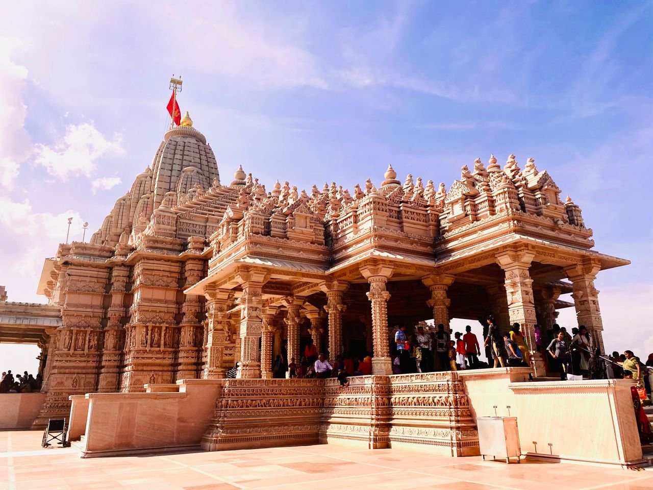 Home An impressive Hindu temple with detailed carvings and a vibrant flag under a clear blue sky.